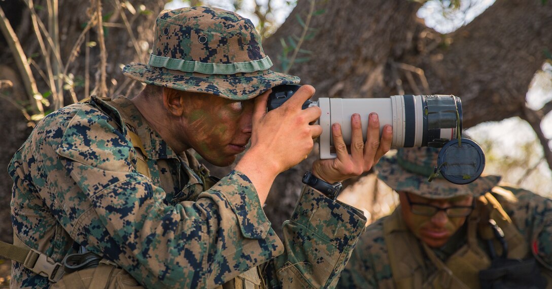 U.S. Marine Corps Lance Cpl. Collin Cummins, left, a radio reconnaissance team point man with 1st Radio Battalion (RADBN), I Marine Expeditionary Force Information Group, photographs simulated enemy activity from a concealed position during a certification exercise at Marine Corps Base Camp Pendleton, California, Oct. 1, 2020. The certification exercise tested 1st RADBN’s ability to conduct tactical recovery of aircraft personnel, radio reconnaissance, and various signals intelligence exercises. (U.S. Marine Corps photo by Lance Cpl. Ian M. Simmons)