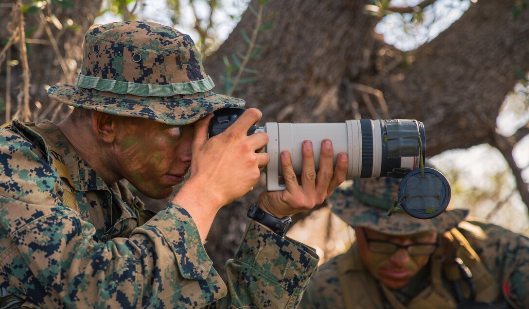 U.S. Marine Corps Lance Cpl. Collin Cummins, left, a radio reconnaissance team point man with 1st Radio Battalion (RADBN), I Marine Expeditionary Force Information Group, photographs simulated enemy activity from a concealed position during a certification exercise at Marine Corps Base Camp Pendleton, California, Oct. 1, 2020. The certification exercise tested 1st RADBN’s ability to conduct tactical recovery of aircraft personnel, radio reconnaissance, and various signals intelligence exercises. (U.S. Marine Corps photo by Lance Cpl. Ian M. Simmons)