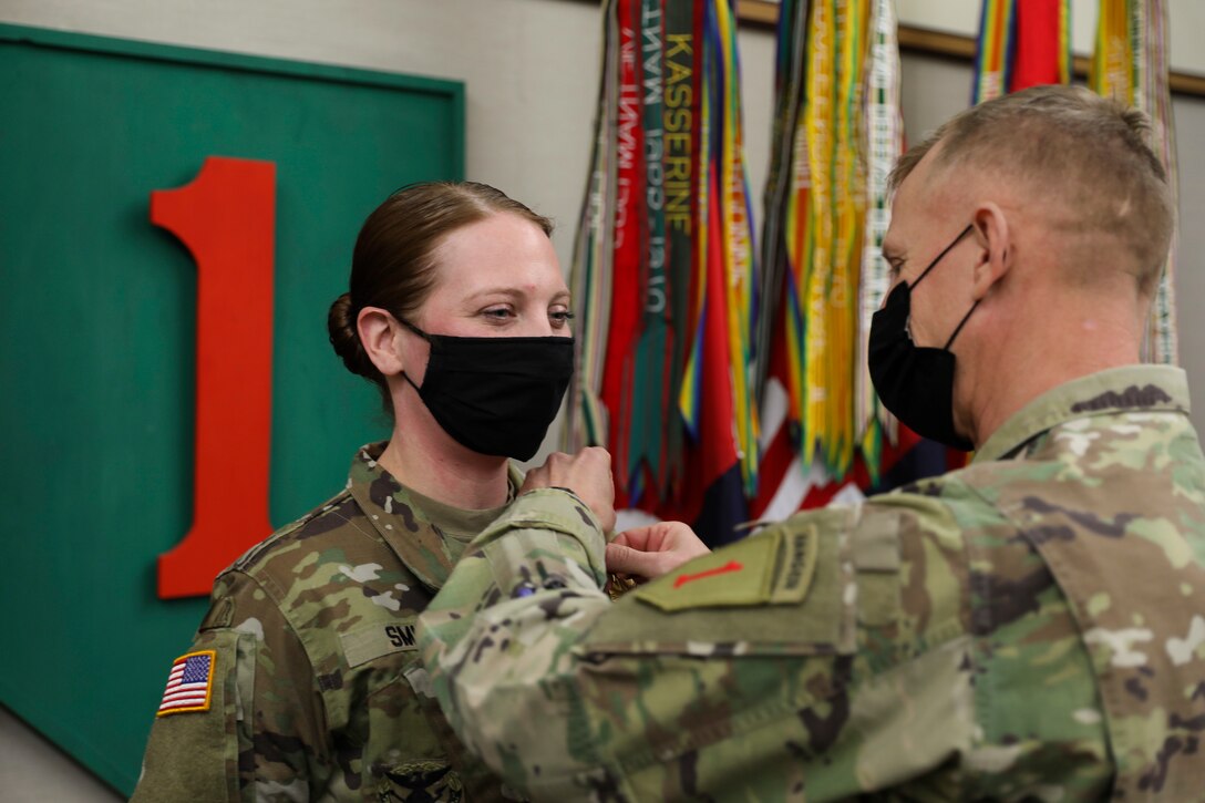 A soldier receives a medal from another soldier.