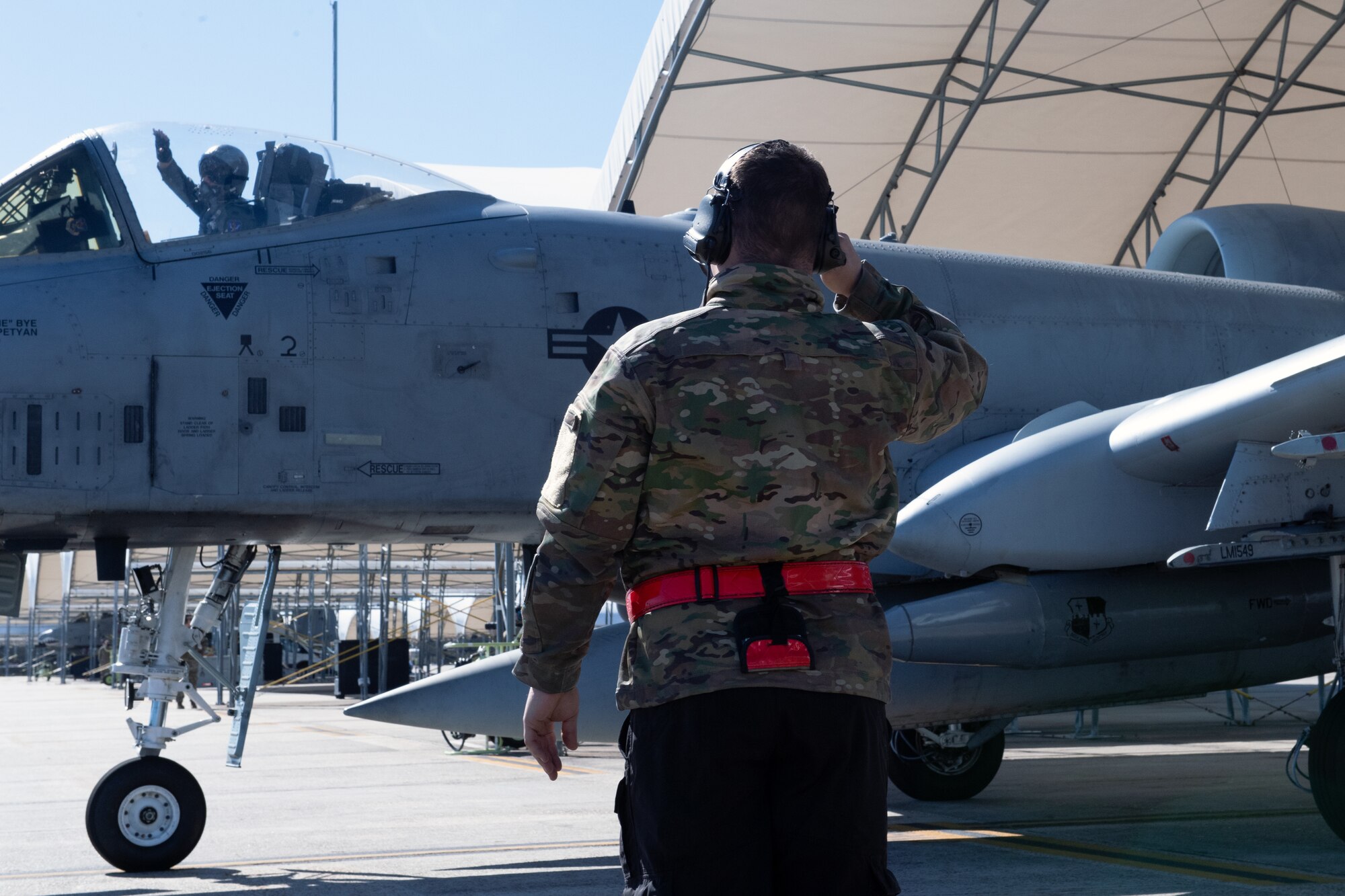 A photo of an Airman saluting an aircraft