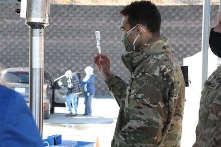 Spc. Trey Pressley, a medic assigned to 236th Brigade Engineer Battalion, 30th Armored Brigade Combat Team, fills a syringe with a COVID-19 vaccine during a drive-through clinic at the Macon County Public Health Department in Franklin, North Carolina, Feb. 3, 2021. North Carolina National Guard Soldiers and Airmen are activated across the state to assist local health departments with increasing vaccine administration efficiency.