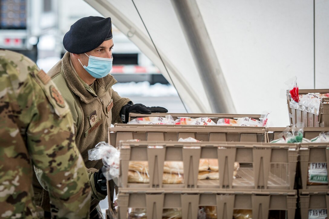 An airman handles trays filled with wrapped bread loaves.