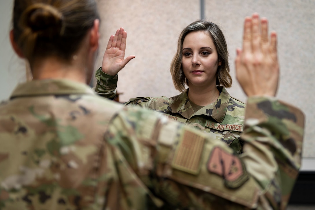 An airman holds up her hand and takes an oath of enlistment.