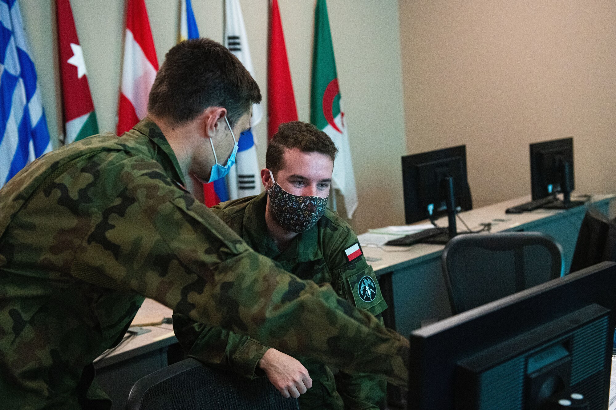 Two Polish Air Force 2nd Lts talk to each other in front of a computer