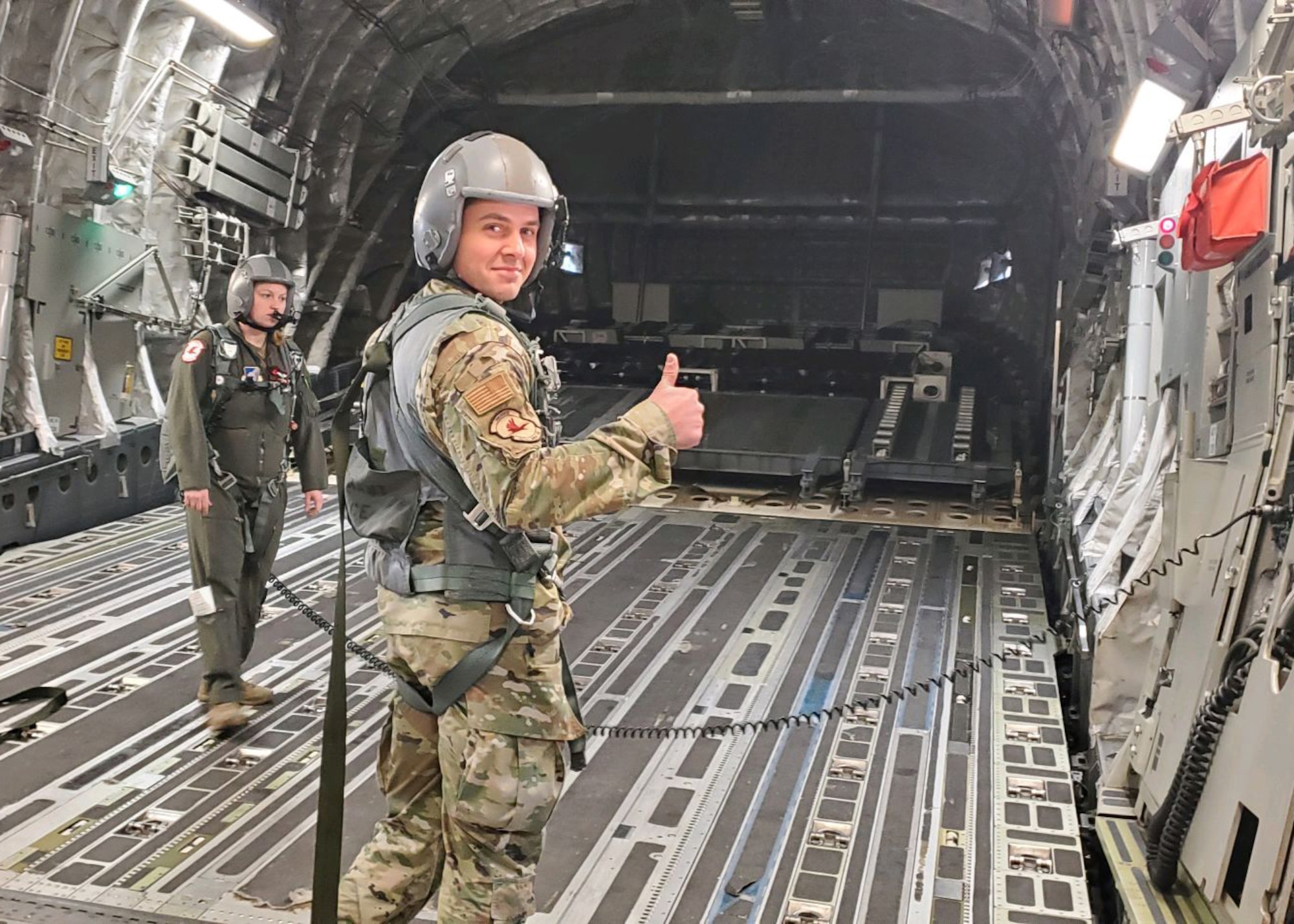 U.S. Air Force Senior Airman Brock Waldrup, a squadron aviation resource manager assigned to the 517th Airlift Squadron, pauses for a photo, while U.S. Air Force Tech. Sgt. Valerie Stephens, a loadmaster with the 517th Airlift Squadron, coordinates with pilots to open the cargo door on a U.S. Air Force C-17A Globemaster III aircraft assigned to the 176th Wing, Alaska Air National Guard, in flight over northwestern Colorado, Jan. 9, 2021. Thirteen Airmen with the 517th AS from Joint Base Elmendorf-Richardson, Alaska, trained for a week in the southwestern U.S. with the C-17, focusing on Agile Combat Employment to train and prepare for global operations in a deployed environment.