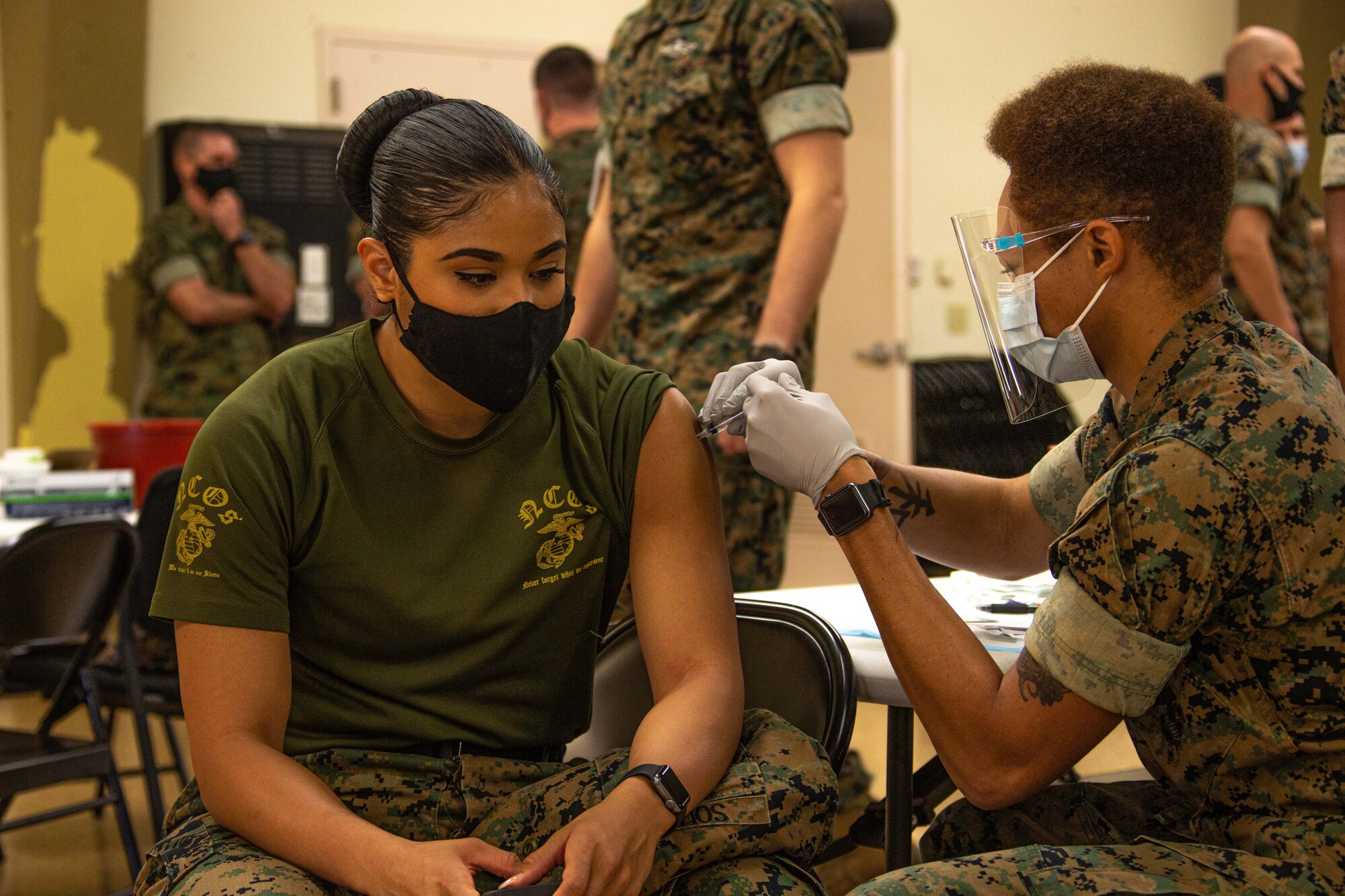 A Marine is inoculated by another service member.