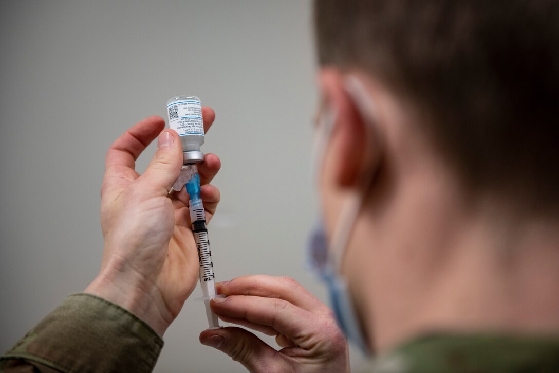 Photo of A medical Airman drawing a COVID-19 vaccine into a syringe.