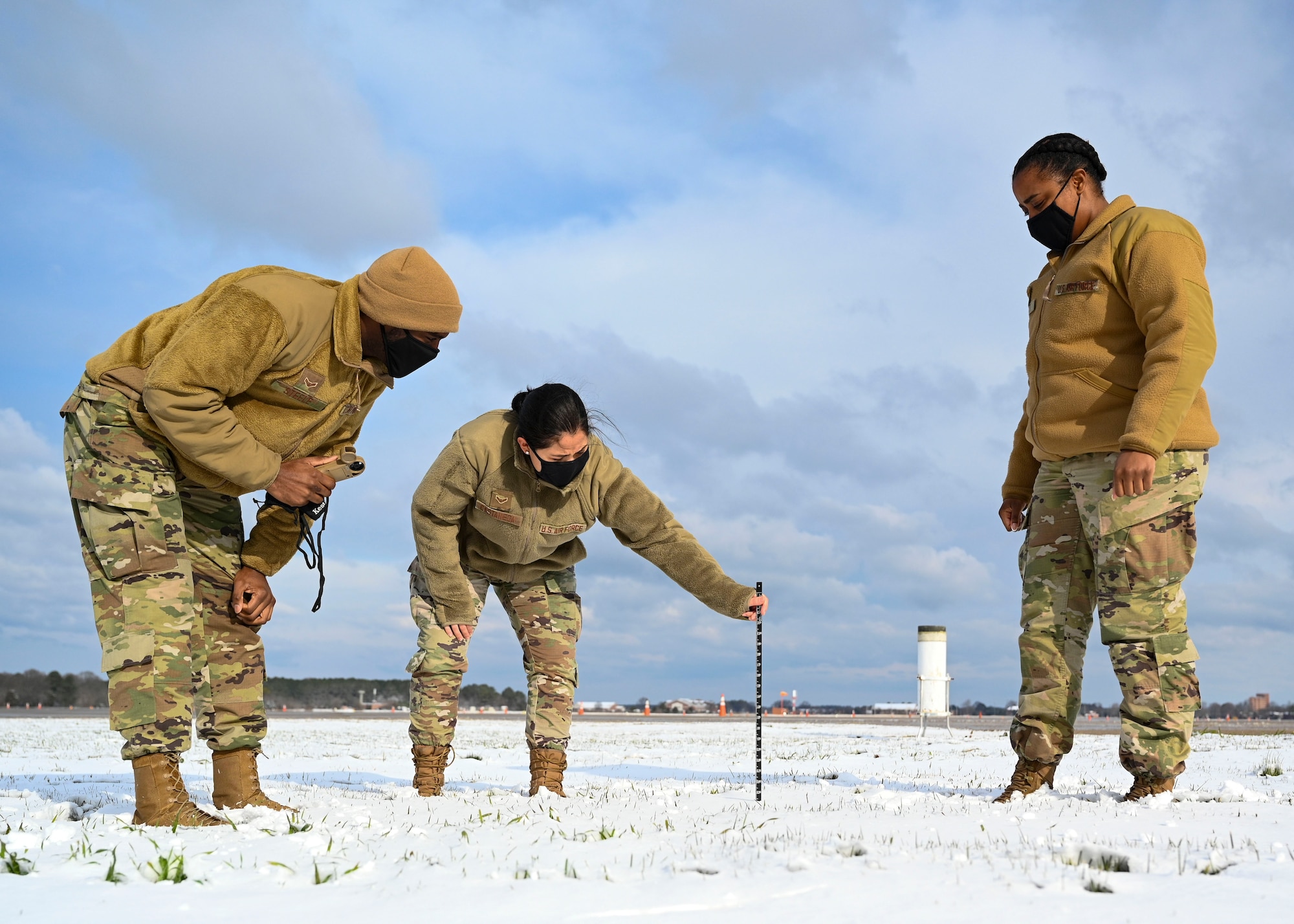 Airmen measuring snow