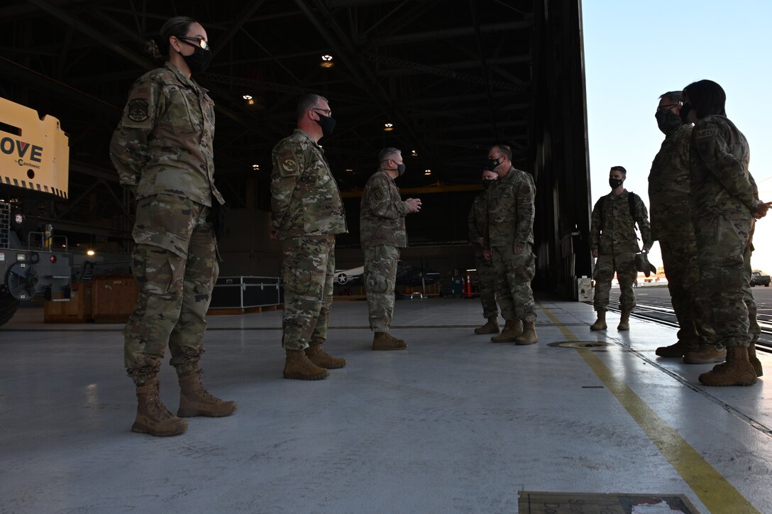 Several people in Air Force uniforms have a stare-down in an aircraft hangar.