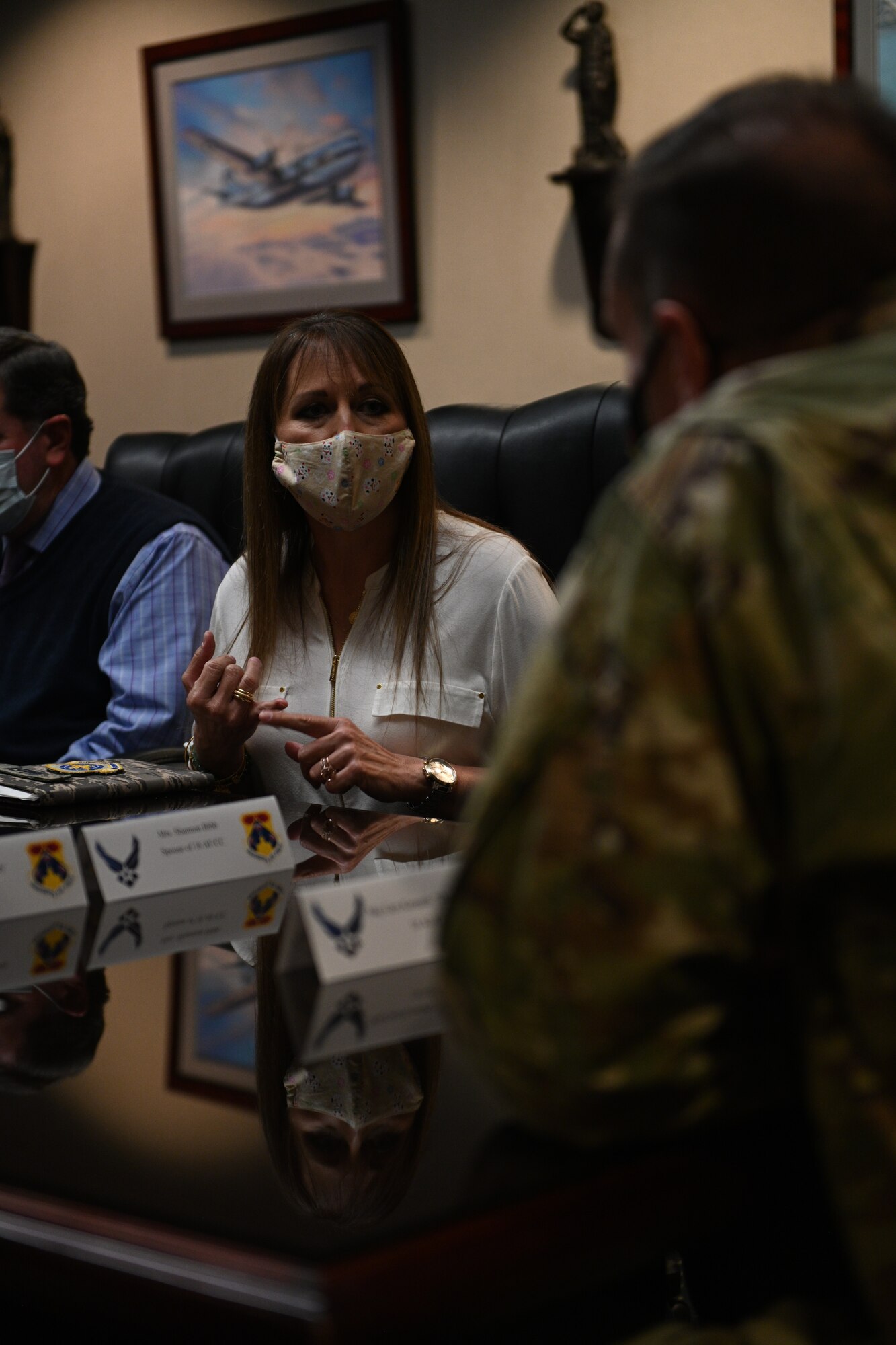 A woman in a mask stares into the camera during a briefing