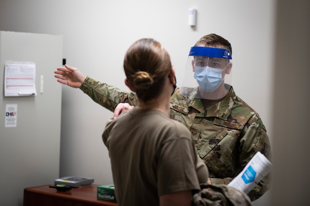 Photo of a Medical Airman directing a patient to the next station in the COVID-19 vaccination pod.