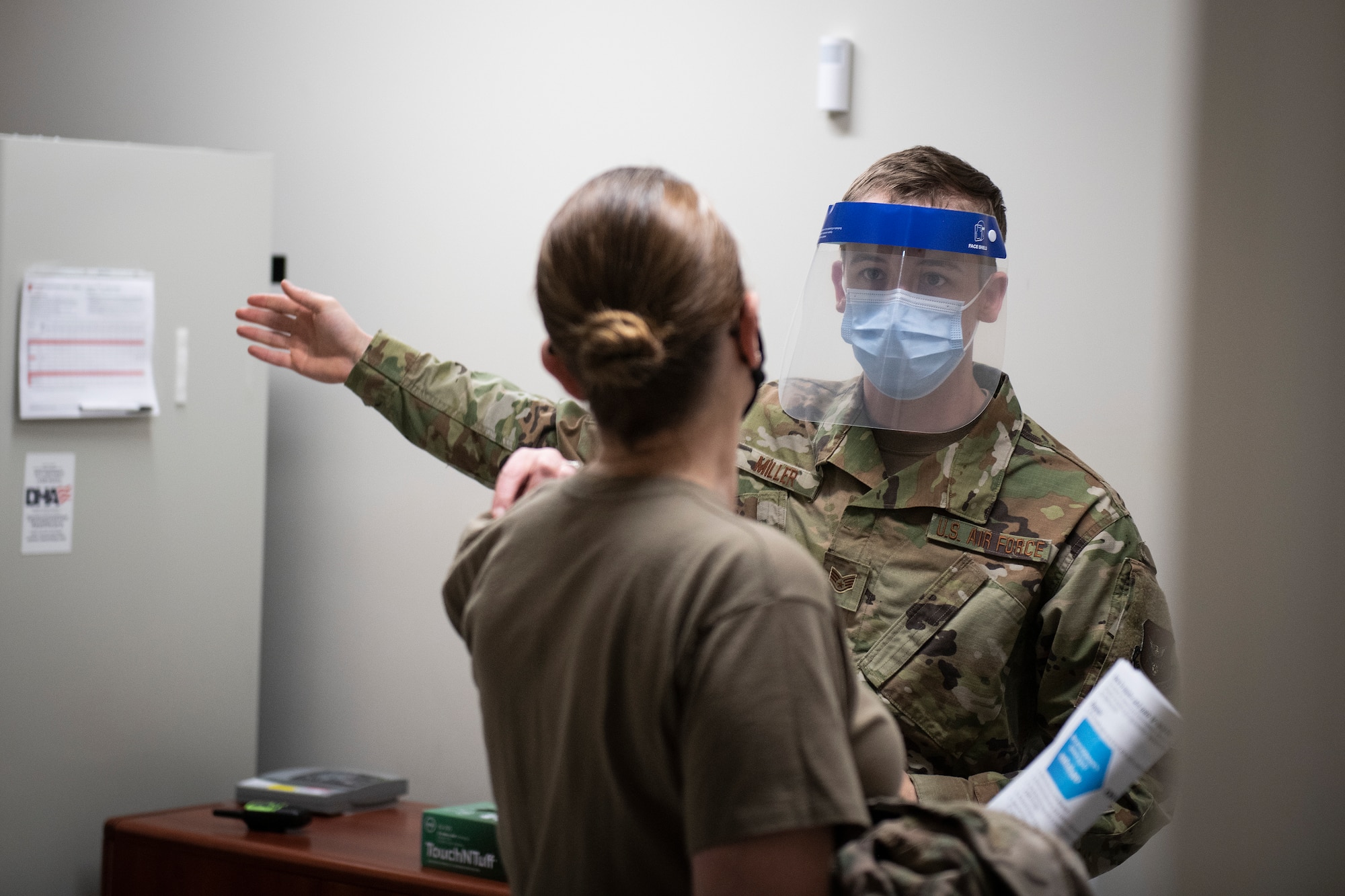 Photo of a Medical Airman directing a patient to the next station in the COVID-19 vaccination pod.
