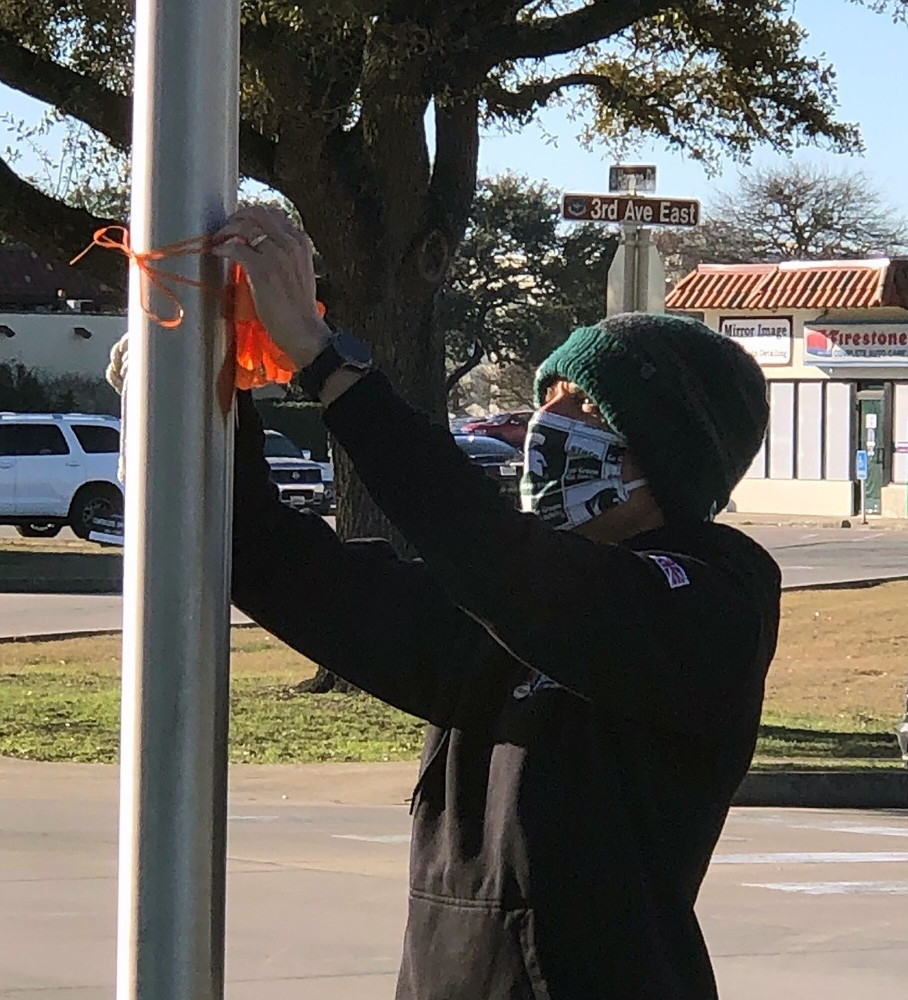Dr. Aaron Moffett, member of the Joint Base San Antonio-Randolph Community Action Team, hangs an orange ribbon on an installation flag pole on bring awareness to Teen Dating Violence Awareness Month Feb. 1.