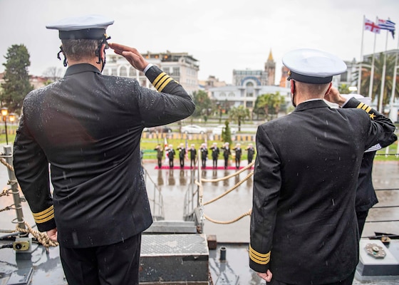 Cmdr. Matthew Curnen, commanding officer of the Arleigh Burke-class guided-missile destroyer USS Donald Cook (DDG 75), left, and Cmdr. Kurt Astroth, executive officer, salute as the American and Georgian national anthems are played during a ceremony in Batumi, Georgia, Feb. 5, 2021.