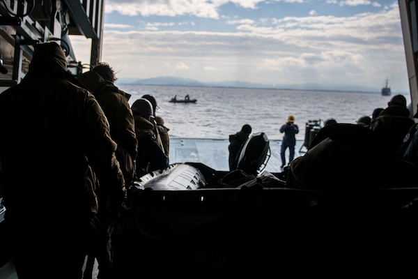 Sailors deployed with Mine Countermeasures Squadron 7 and members of the Japan Maritime Self-Defense Force (JMSDF) move a combat rubber raiding craft aboard the minesweeper tender JS Uraga (MST 463) during Mine Warfare Exercise (MINEX) 1JA 2021.