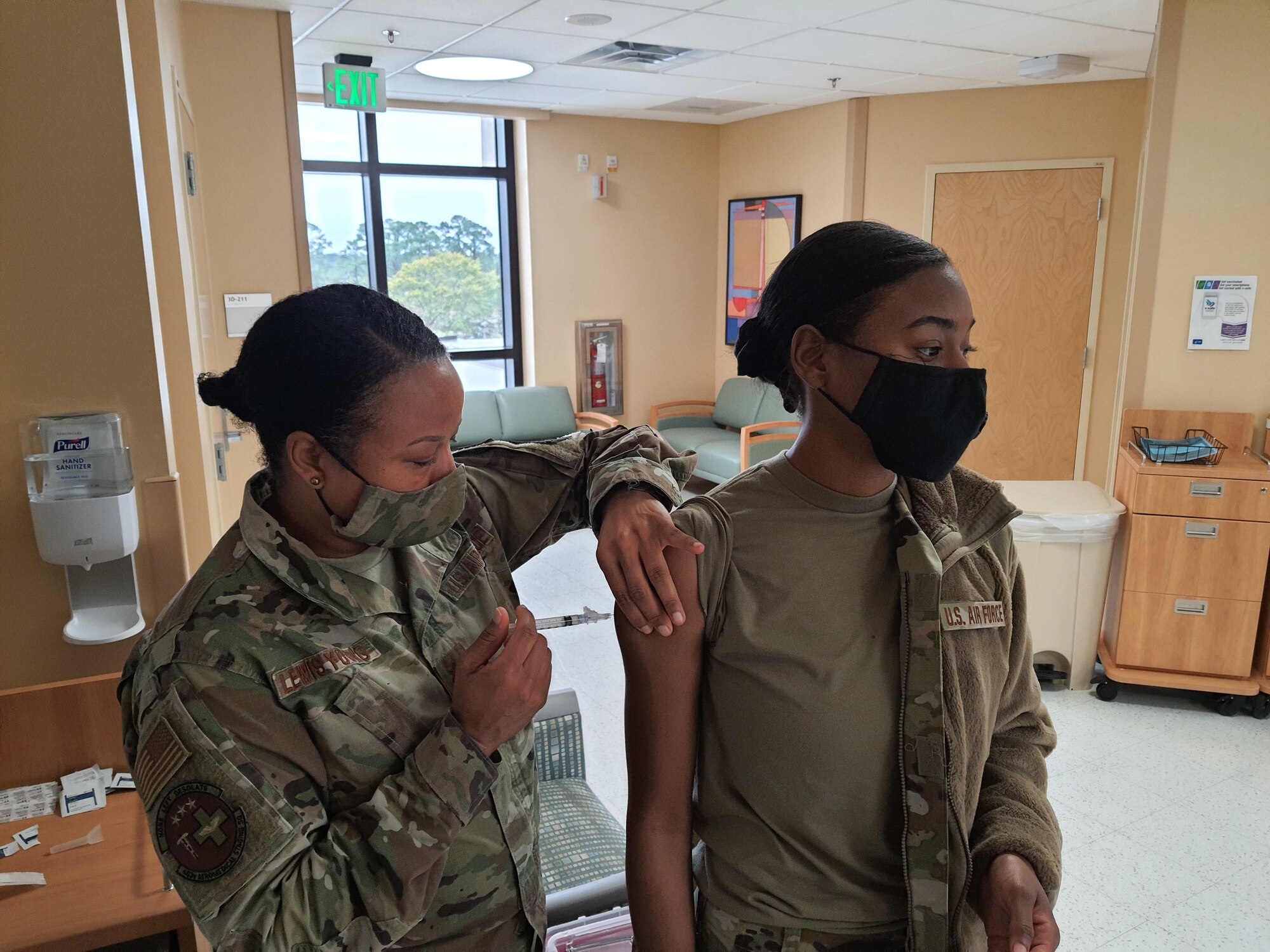 Maj. Angela Lewis-Young, 403rd Aeromedical Staging Squadron nurse, administers the first dose of the COVID vaccine to Senior Airman Rachel Smith, 403rd ASTS medical technician, Feb. 6, 2021. These were literal firsts for the 403rd Wing. The wing first received the vaccine for the February Unit Training Assembly, Lewis-Young administered the first dose at the Wing, and Smith received the first dose. (U.S. Air Force photo by Master Sgt. Jessica Kendziorek/ Photo permission granted by Senior Airman Rachel Smith)