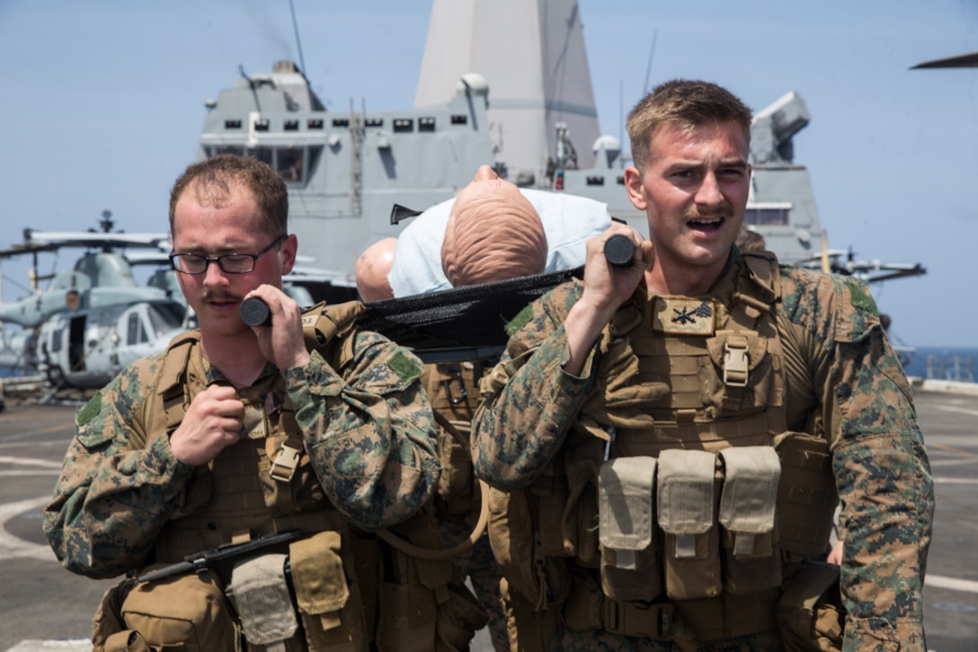 210126-M-JX780-1057 INDIAN OCEAN (Jan. 26, 2021) – U.S. Marine Corps Lance Cpl. Jonathan Tiscareno, left, a field artillery fire control man with Battalion Landing Team 1/4, 15th Marine Expeditionary Unit, and Sgt. Matthew Coffman, a high mobility artillery rocket system launcher chief, with HIMARS Detachment, BLT 1/4, 15th MEU, squat with a litter during a tactical casualty care course aboard the amphibious transport dock ship USS Somerset (LPD 25). The Makin Island Amphibious Ready Group and the 15th MEU are conducting operations in the U.S. 6th Fleet area of responsibility. (U.S. Marine Corps photo by Lance Cpl. Brendan Mullin)