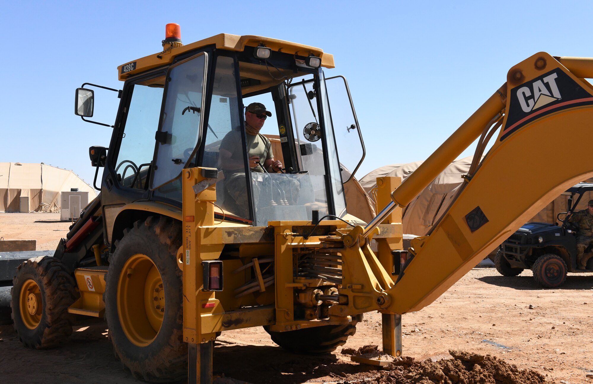 U.S. Air Force Master Sgt. Sean Kerrigan, 724th Expeditionary Air Base Squadron Civil Engineer Flight water and fuels maintenance shop supervisor, operates a backhoe to remove dirt around a ruptured water main at Nigerien Air Base 201, Agadez, Niger, Feb. 2, 2021. The civil engineer team successfully located and repaired the water main break that was overflowing a communications manhole. (U.S. Air Force photo by Senior Airman Gabrielle Winn)