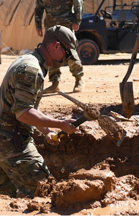 U.S. Air Force Staff Sgt. Coleman Crowell, 724th Expeditionary Air Base Squadron Civil Engineer Flight water and fuels maintenance craftsman, uses a pickaxe to locate a burst pipe at Nigerien Air Base 201, Agadez, Niger, Feb. 2, 2021. A rupture of this magnitude would’ve taken days to accomplish, but only took a few hours due to knowing the exact location. (U.S. Air Force photo by Senior Airman Gabrielle Winn)
