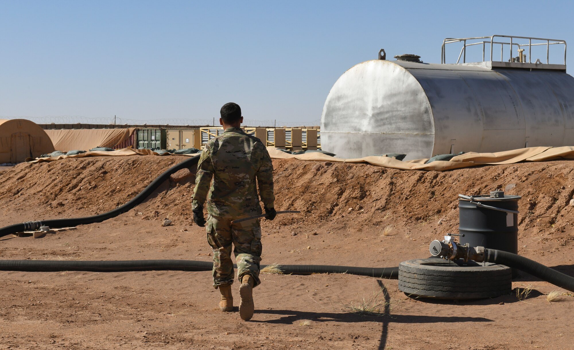 U.S. Air Force Staff Sgt. Josue Ruiz-Garcia, 724th Expeditionary Air Base Squadron fuel operations noncommissioned officer in charge, walks to a fuel tank to measure the volume of fuel at Nigerien Air Base 201, Agadez, Niger, Feb. 2, 2021. Measuring the volume of fuel allows the petroleum, oils, and lubrication fuels Airmen to accurately account for all the fuel they have on base. (U.S. Air Force photo by Senior Airman Gabrielle Winn)
