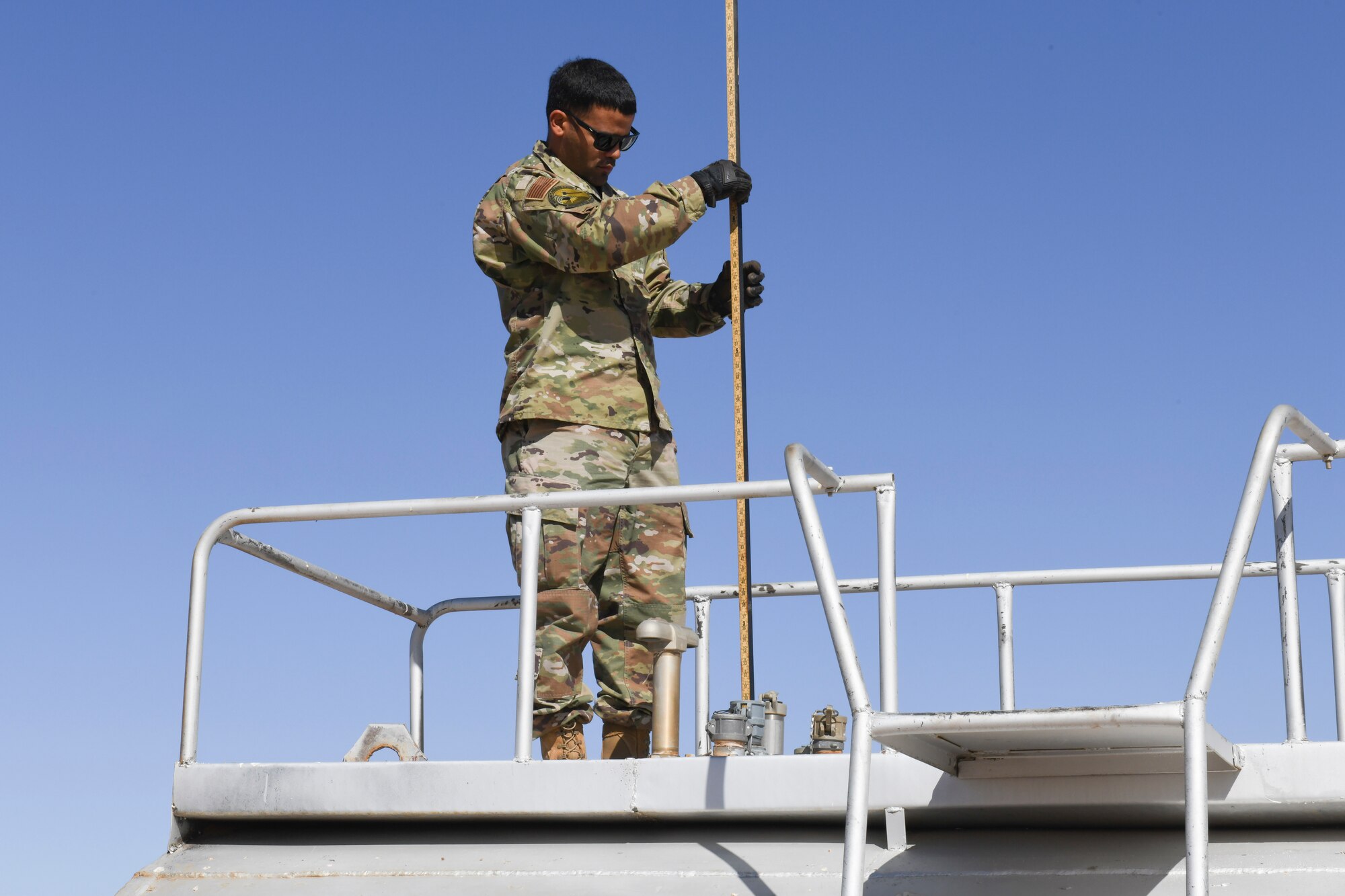U.S. Air Force Staff Sgt. Josue Ruiz-Garcia, 724th Expeditionary Air Base Squadron fuel operations noncommissioned officer in charge, uses a sticking tank to get an accurate measurement of how much fuel is in the fuel tank at Nigerien Air Base 201, Agadez, Niger, Feb. 2, 2021. Getting an accurate read on how much volume the tank contains can determine when the petroleum, oil, and lubrication fuels section needs to order more fuel to keep the base stocked. (U.S. Air Force photo by Senior Airman Gabrielle Winn)