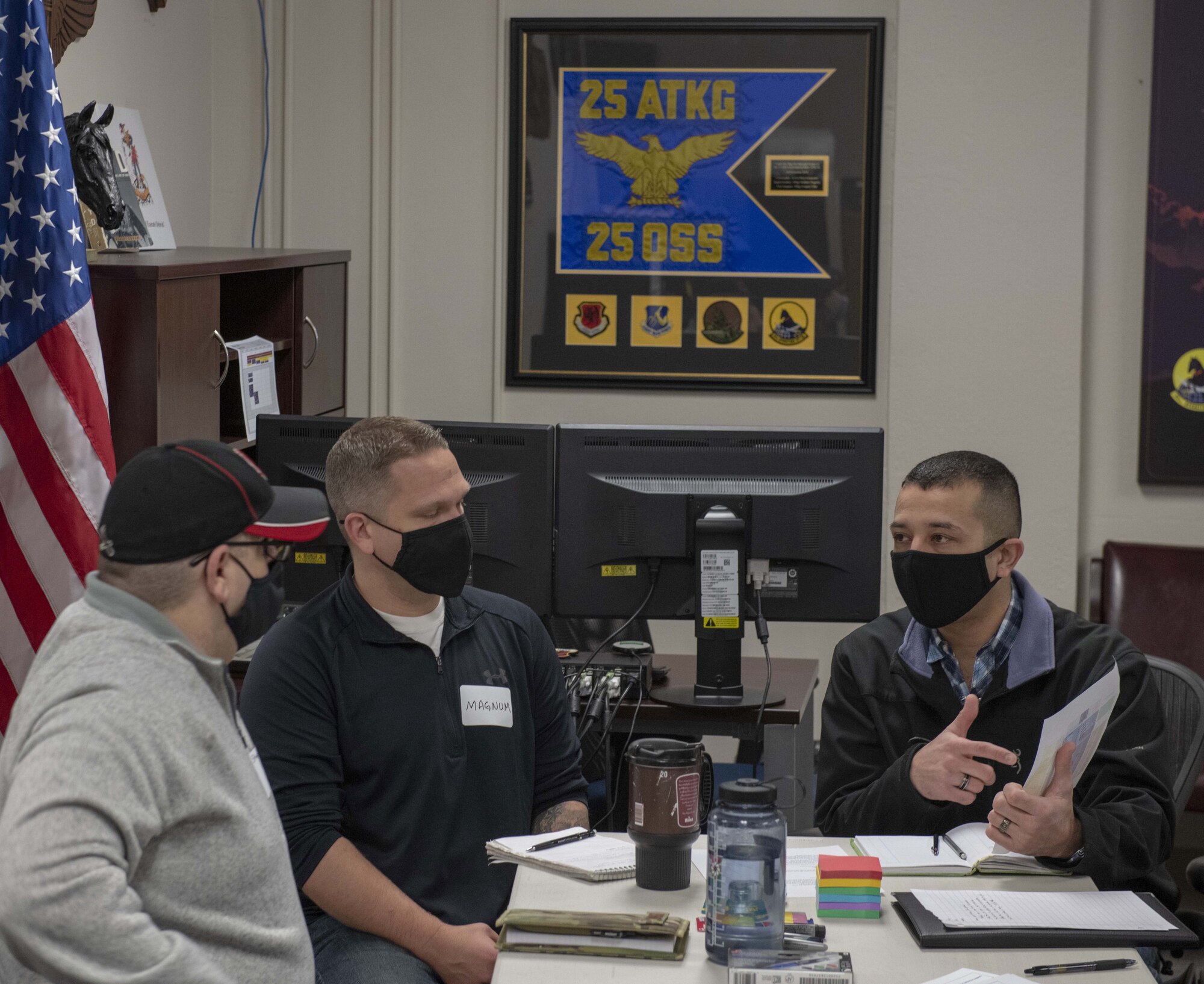 U.S. Air Force Master Sgt. Steven, 25th Operations Support Squadron (OSS) weather flight chief, left, and Capt. Patrick, 25th OSS assistant chief of wing weapons, center, listen to Capt. Juan, 20th Attack Squadron assistant director of operations speak to each other in a group planning session.