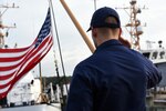A crew member aboard Cutter Flying Fish salutes after hoisting the flag during morning colors.