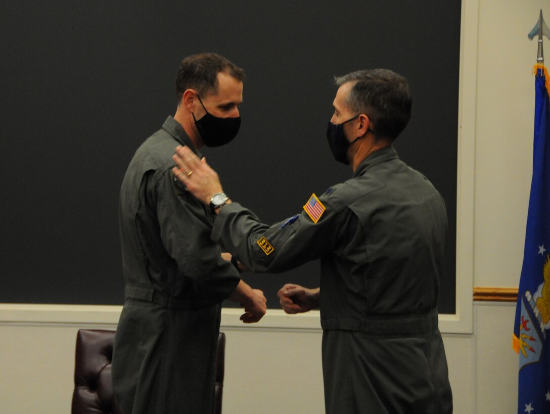 Lt. Col. Jason Allen (right), outgoing commander of the 313th Airlift Squadron, gives badges to Lt. Col. Joshua Anderson (left), incoming squadron commander, during a change of command ceremony  Feb. 6, 2021, at Joint Base Lewis-McChord, Washington