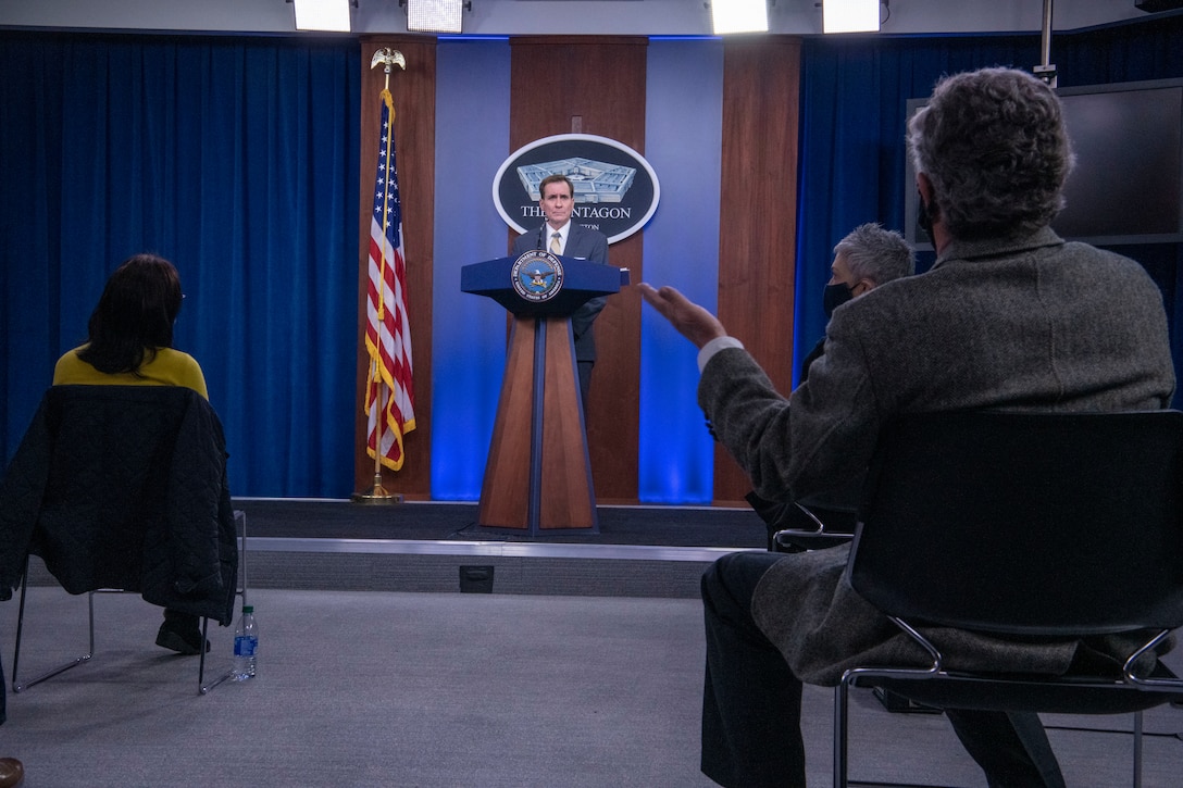 A man at a lectern answers questions from an audience of reporters.. A sign indicating that he is at the Pentagon is behind him.
