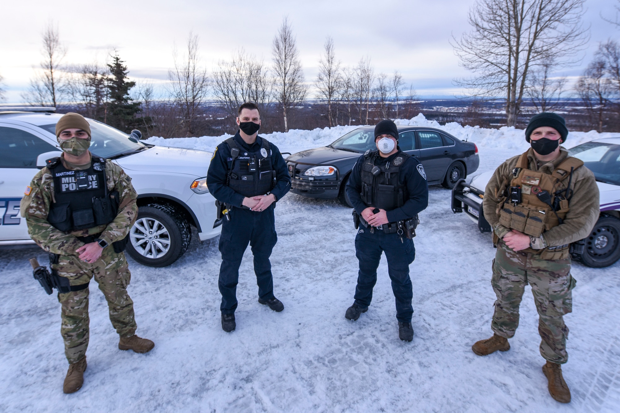 From left: U.S. Army Sgt. Hori Martinez Munoz, Patrolman assigned to the 545th Military Police Detachment, Department of Defense Police Officer Richard Martinez, assigned to the 673d Security Forces Squadron, Officer Joey Giammalva with the Anchorage Police Department, and U.S. Air Force Staff Sgt. Alexander Peppers, a 673 SFS patrolman and recent graduate of the APD Police Academy stand in front of their patrol cars at Joint Base Elmendorf-Richardson, Alaska, Jan 21, 2021. The evolving partnership between the 673d SFS and APD has continued to develop over the past few years leading to noticeable benefits for the entire community. Recent examples include, but are not limited to; catching a reckless motorcycle on the Glenn Hwy at speeds of over 100+ mph, finding and stopping a stolen vehicle, finding and arresting a drunk driver, and making arrests on wanted individuals.