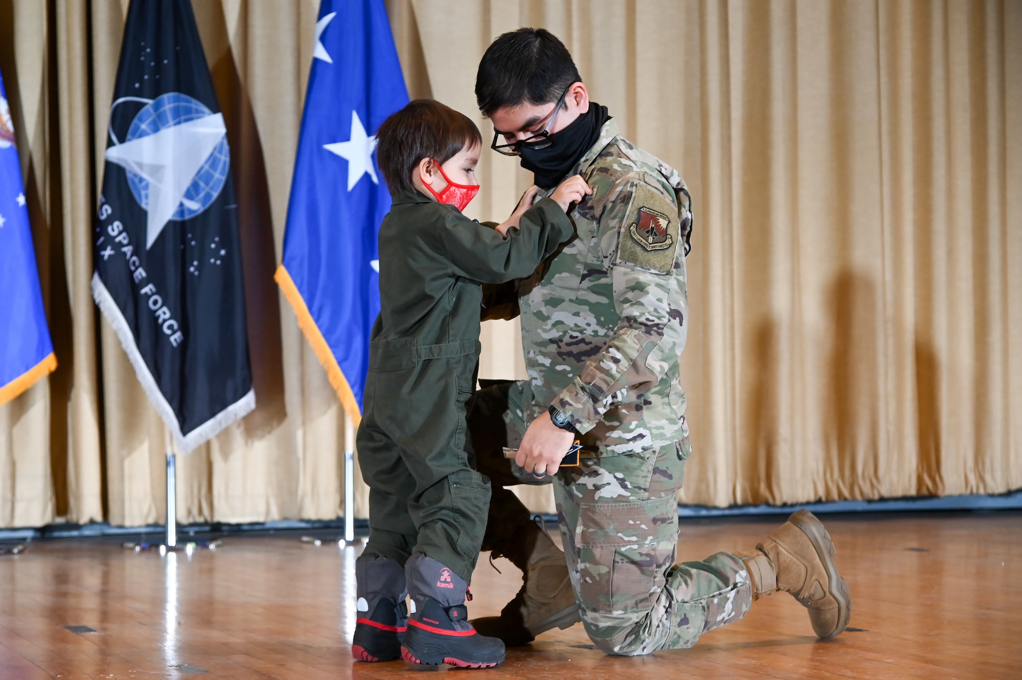 Captain Sergio Martinez, Air Force Life Cycle Management Center, gets his patches replaced by his son at the U.S. Air Force Space Induction Ceremony Feb. 5, 2020