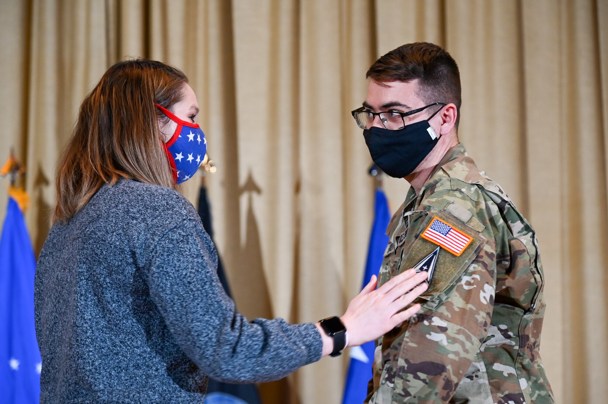 Specialist 4 Jake Sevier, 729th Air Control Squadron, has his patches replaced by his wife