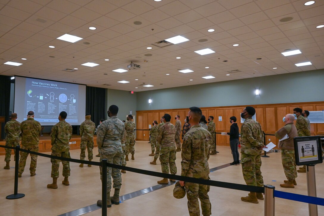 A group of people listen to a briefing about the COVID-19 vaccine