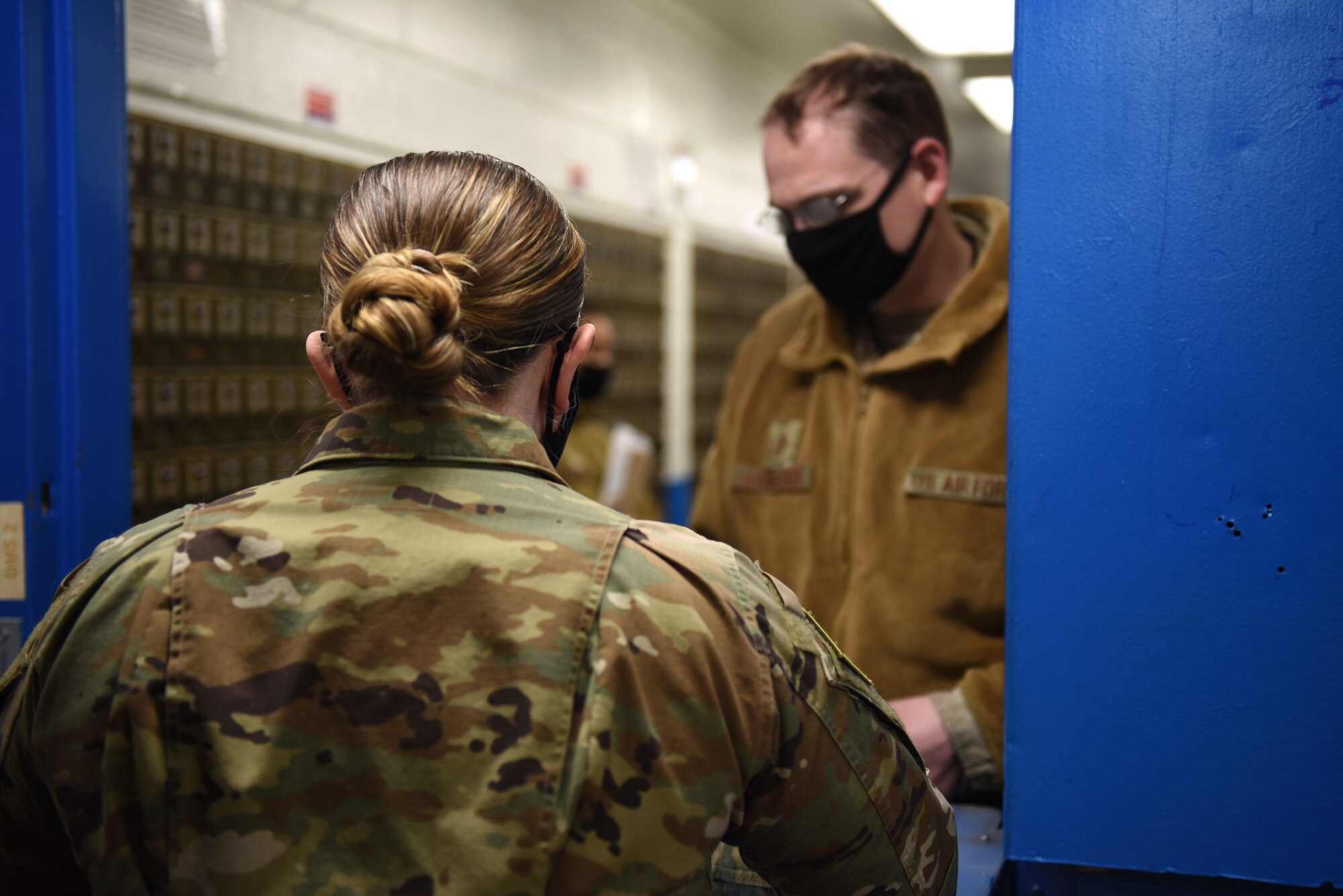 Tech. Sgt. Heather Head, 8th Force Support Squadron postal operations NCO in-charge, gives mail to Master Sgt. Daniel Hansford, 8th Maintenence Squadron mission support equipment maintenance NCO in-charge, inside the post office at Kunsan Air Base, Republic of Korea, Feb. 3, 2021. With a staff of 11, the post office receives and distributes approximately 5,000 packages a week to the base.
