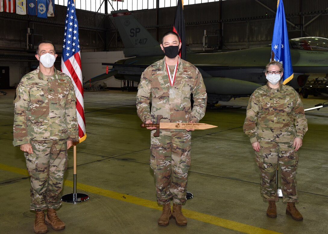 U.S. Air Force Col. Jason Hokaj, 52nd Fighter Wing vice commander (left), and Chief Master Sgt. Stephanie Cates, 52nd Fighter Wing command chief (right), give the Field Grade Officer of the Year award to U.S. Air Force Maj. William Hinchey, 52nd Munitions Maintenance Group, Feb. 5, 2021, at Spangdahlem Air Base, Germany.
