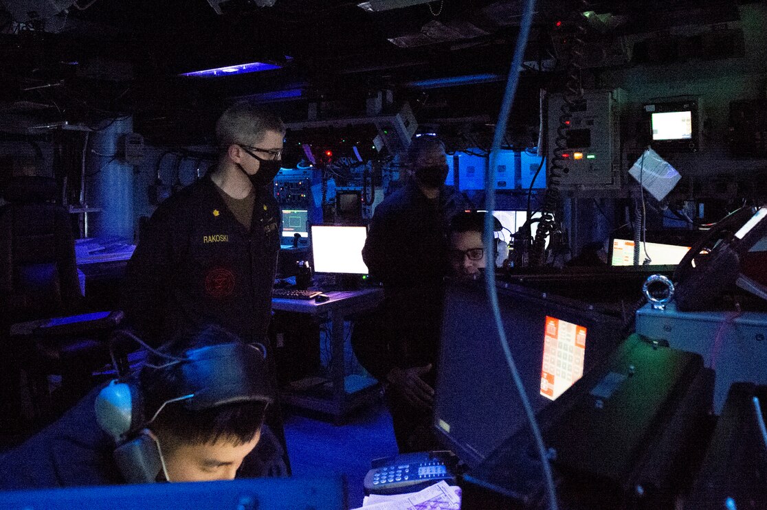 PACIFIC OCEAN (Jan. 13, 2021) Naval Surface and Mine Warfighting Development Center’s (SMWDC’s) Lt. Cmdr. Chris Rakoski, an Anti-Submarine Warfare/Surface Warfare (ASW/SUW) Warfare Tactics Instructor (WTI), from Montesano, Wash., advises Combat Information Center (CIC) watchstanders aboard the Wasp-class amphibious assault ship USS Essex (LHD 2). Essex is underway conducting routine operations in the U.S. Third Fleet area of operations. (U.S. Navy Photo by Mass Communication Specialist 2nd Class Devin Alexondra Lowe)