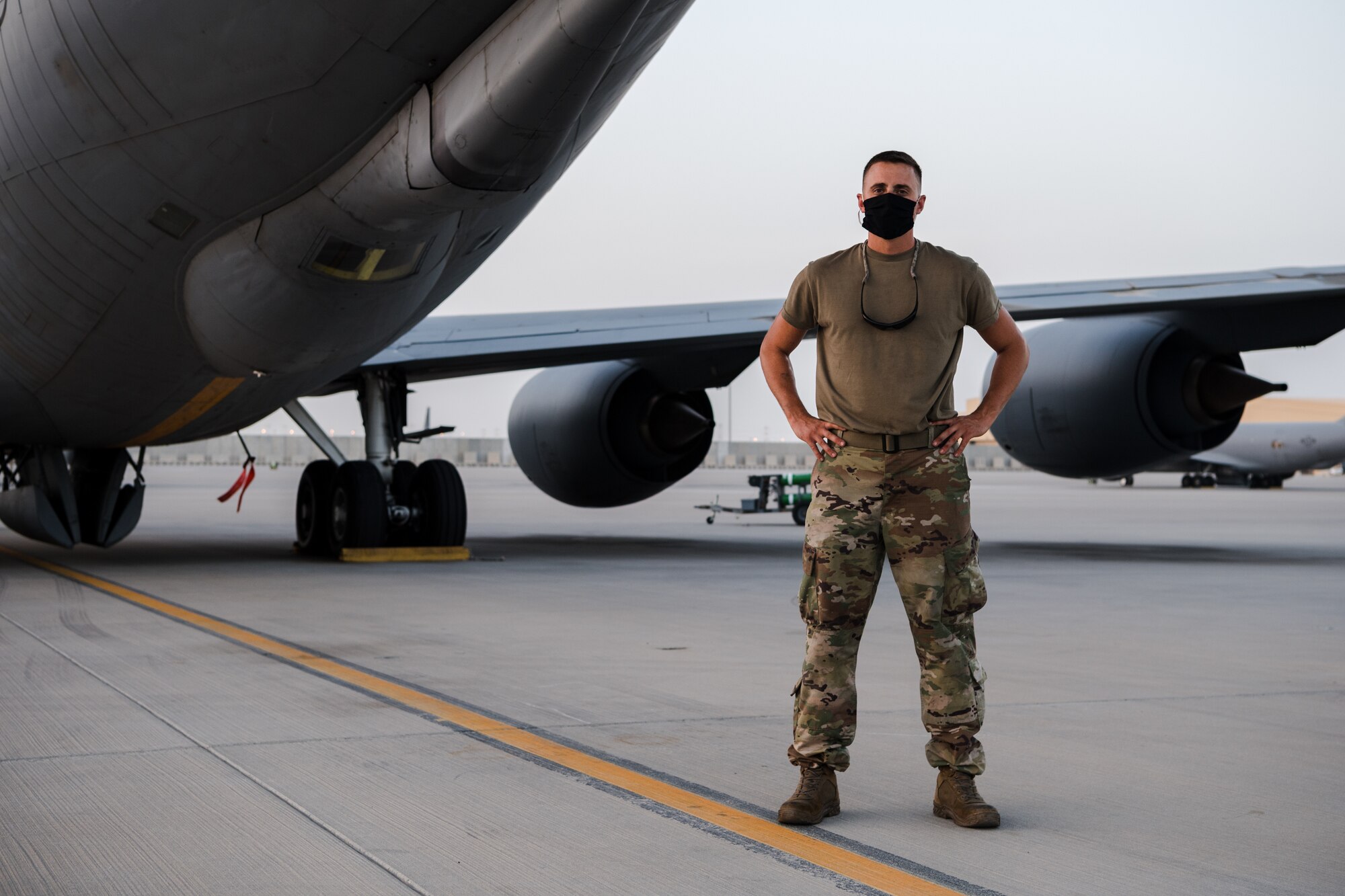 U.S. Air Force Tech. Sgt. stands on flightline posing in COVID mask.