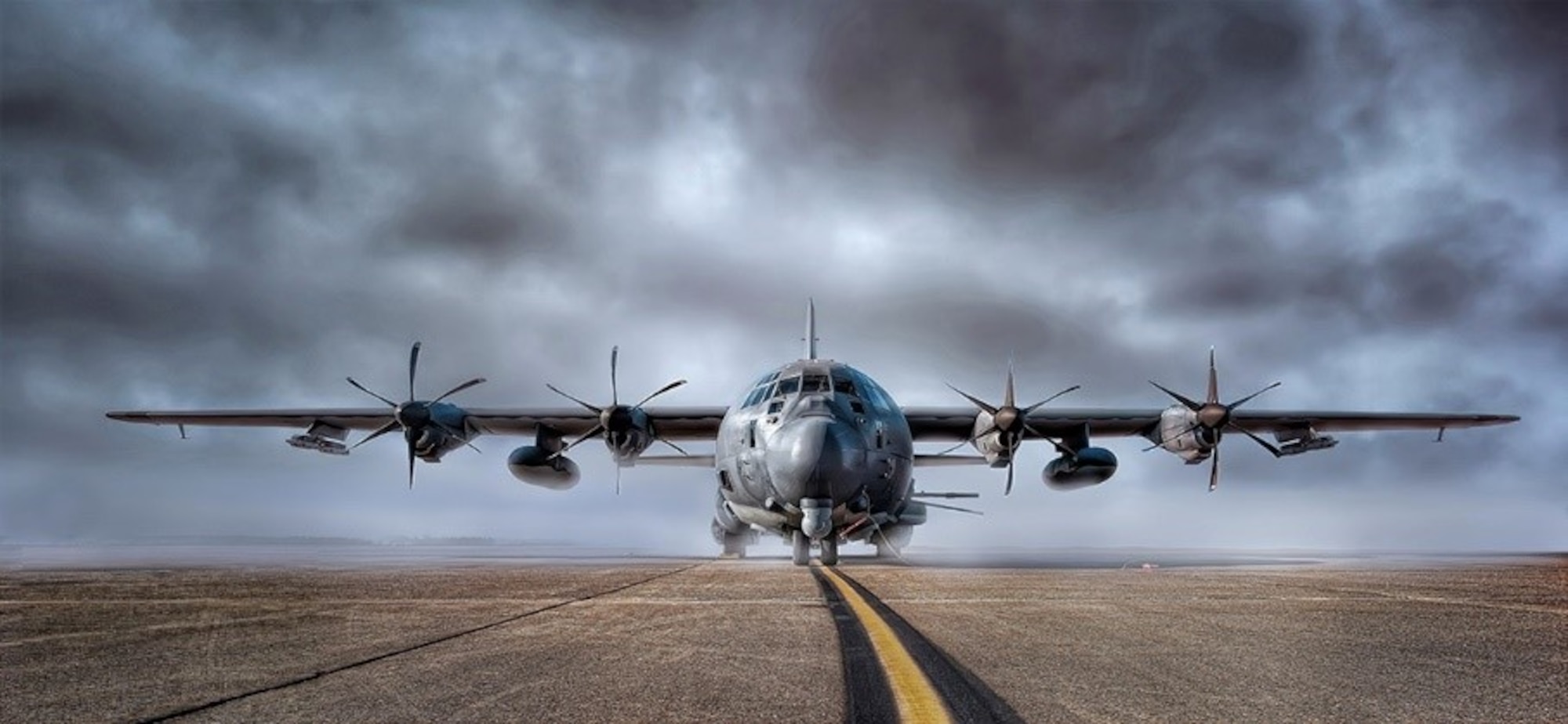 Photo of an aircraft on a flightline with clouds in the background.