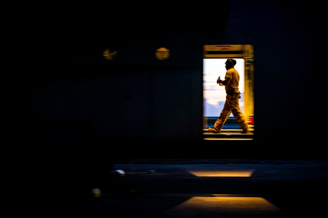 An airman walks past a doorway.