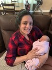 Personnel Specialist Chief (PSC) Veronica Guadalupe Foley poses for a photo while holding her newborn daughter
