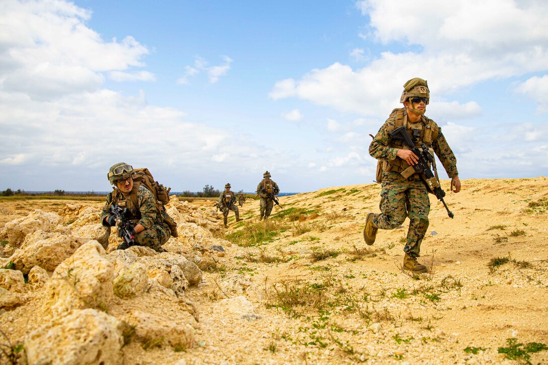 Four Marines move through desert terrain.