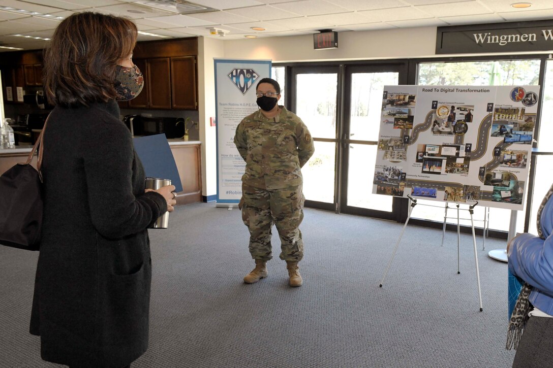 Photo shows two women standing near an easel with a poster board on it.