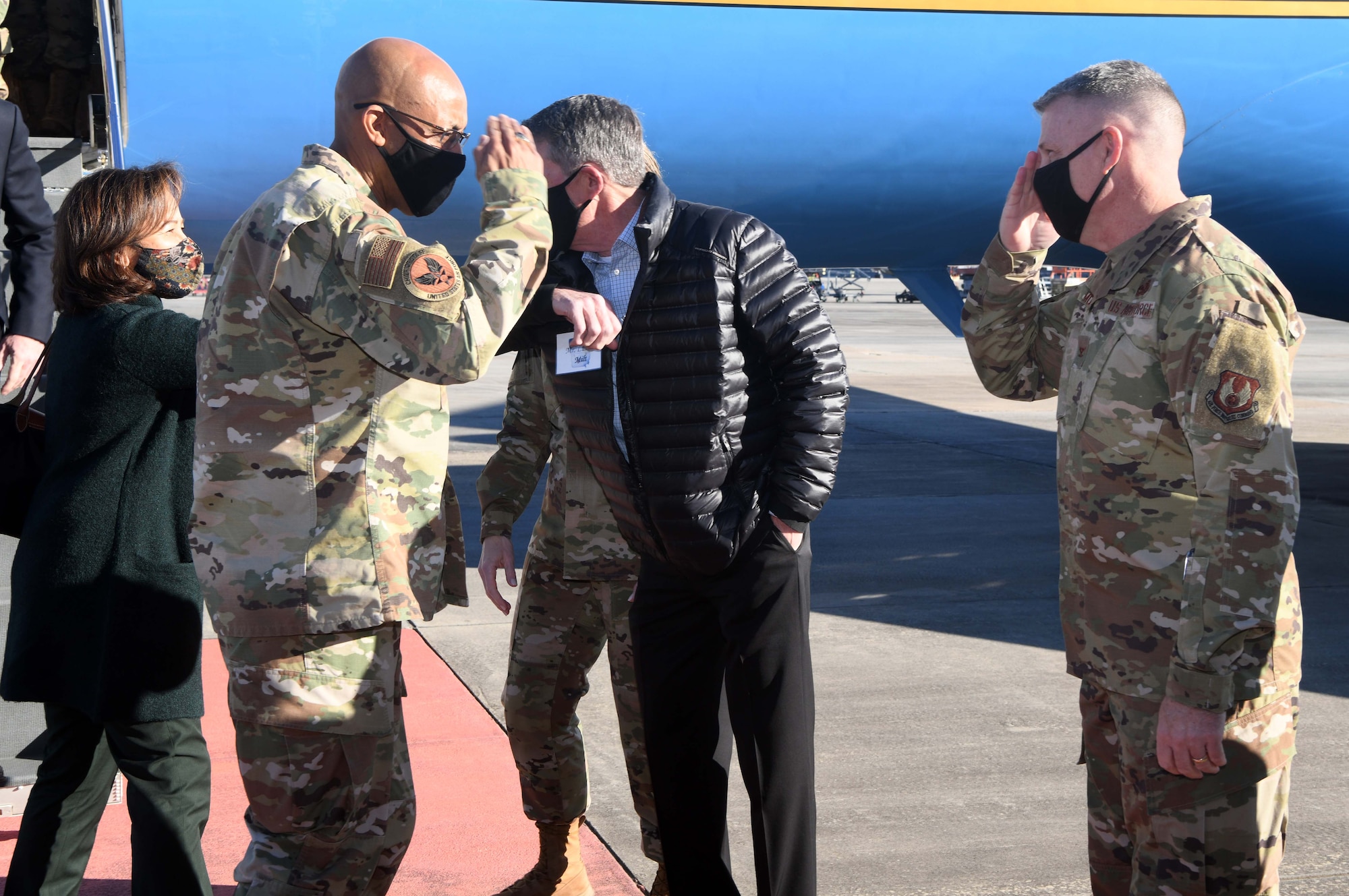 Photo shows two men standing in front of aircraft saluting each other.