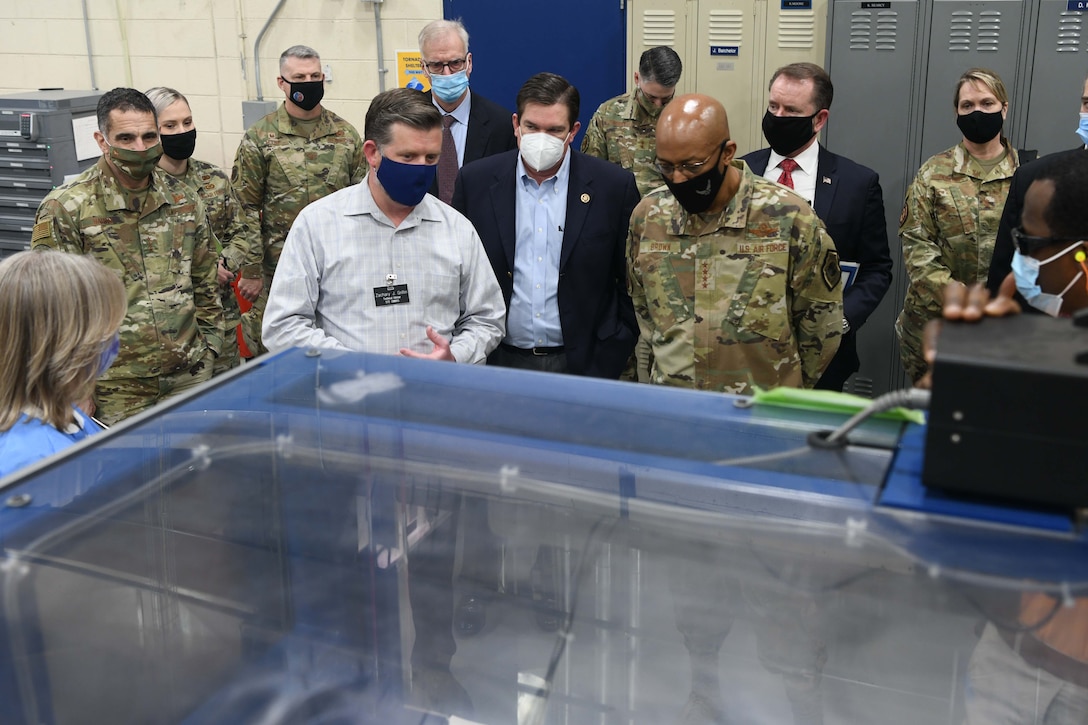 Photo shows group of people looking into a square machine.