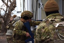 Defends with rifles look into the back of a payload transporter van with the intent of moving into the van and neutralizing the threat.