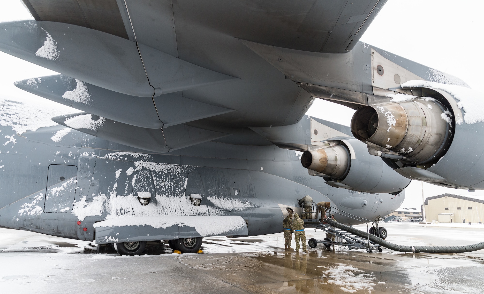 Maintainers from the 736th Aircraft Maintenance Squadron, walk toward a C-17 Globemaster III to check on repairs being made to the aircraft’s auxiliary power unit door at Dover Air Force Base, Delaware, Feb. 7, 2021. As snow fell, the base continued normal operations and prepared for additional snowfall. (U.S. Air Force photo by Roland Balik)
