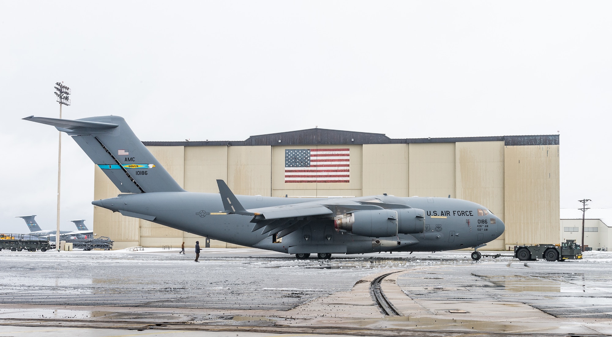 A maintenance tow team from the 736th Aircraft Maintenance Squadron, tow a C-17 Globemaster III from the flight line into a hangar to facilitate maintenance out of the weather at Dover Air Force Base, Delaware, Feb. 7, 2021. As snow fell, the base continued normal operations and prepared for additional snowfall. (U.S. Air Force photo by Roland Balik)