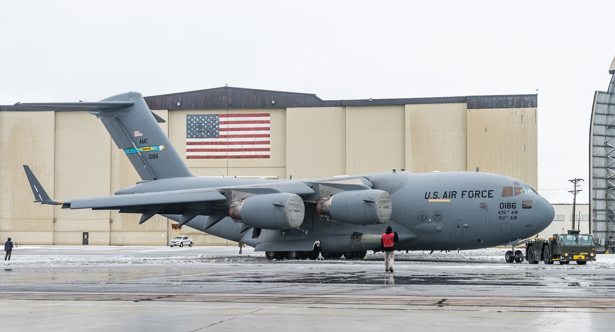 A maintenance tow team from the 736th Aircraft Maintenance Squadron, tow a C-17 Globemaster III from the flight line into a hangar to facilitate maintenance out of the weather at Dover Air Force Base, Delaware, Feb. 7, 2021. As snow fell, the base continued normal operations and prepared for additional snowfall. (U.S. Air Force photo by Roland Balik)