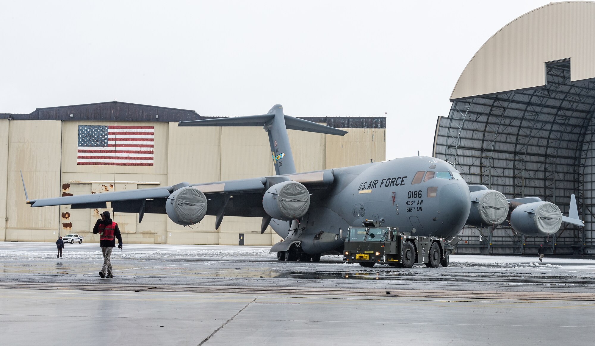 A maintenance tow team from the 736th Aircraft Maintenance Squadron, tow a C-17 Globemaster III from the flight line to a hangar to facilitate maintenance out of the weather at Dover Air Force Base, Delaware, Feb. 7, 2021. As snow fell, the base continued normal operations and prepared for additional snowfall. (U.S. Air Force photo by Roland Balik)