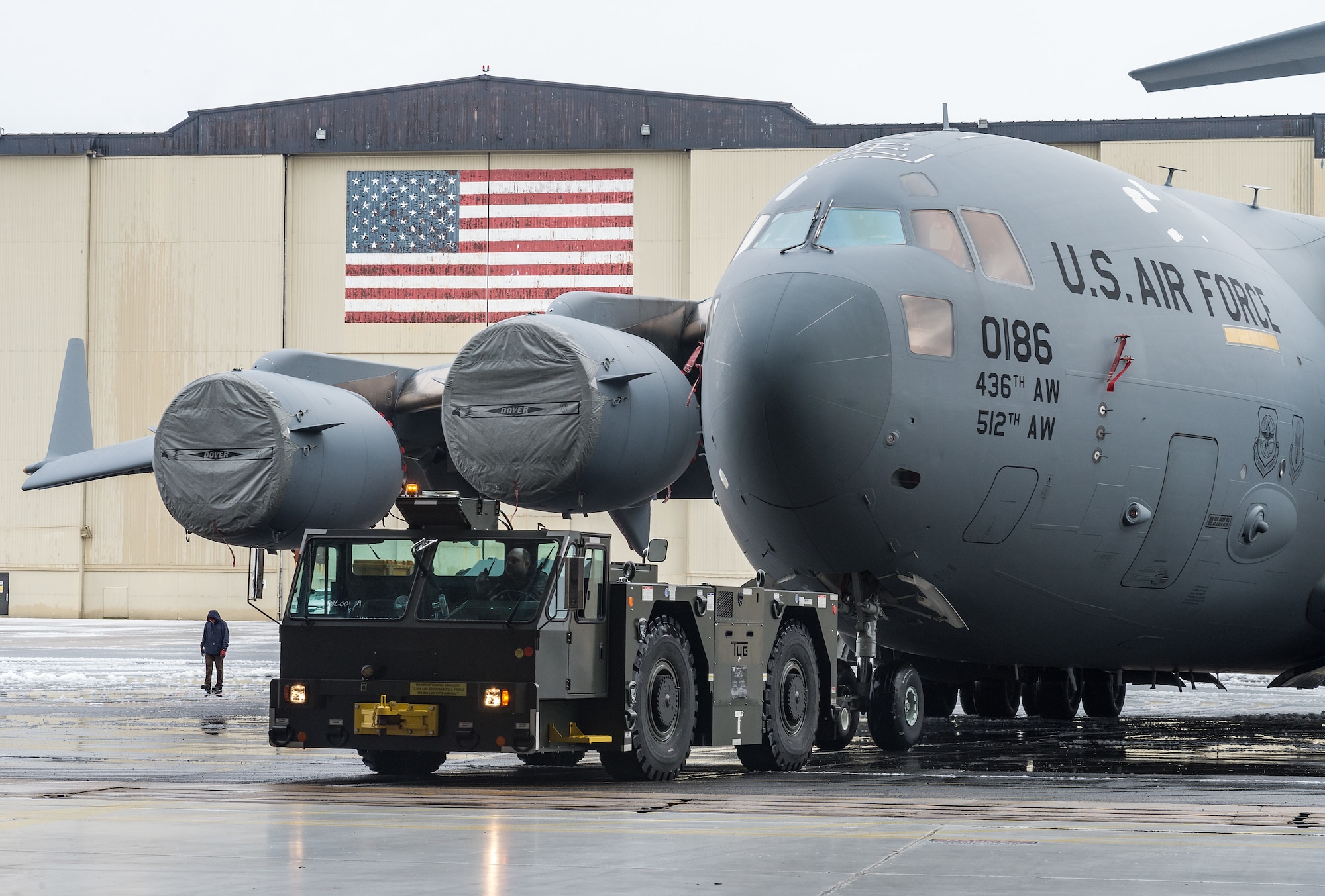 A maintenance tow team from the 736th Aircraft Maintenance Squadron, tow a C-17 Globemaster III from the flight line to a hangar to facilitate maintenance out of the weather at Dover Air Force Base, Delaware, Feb. 7, 2021. As snow fell, the base continued normal operations and prepared for additional snowfall. (U.S. Air Force photo by Roland Balik)